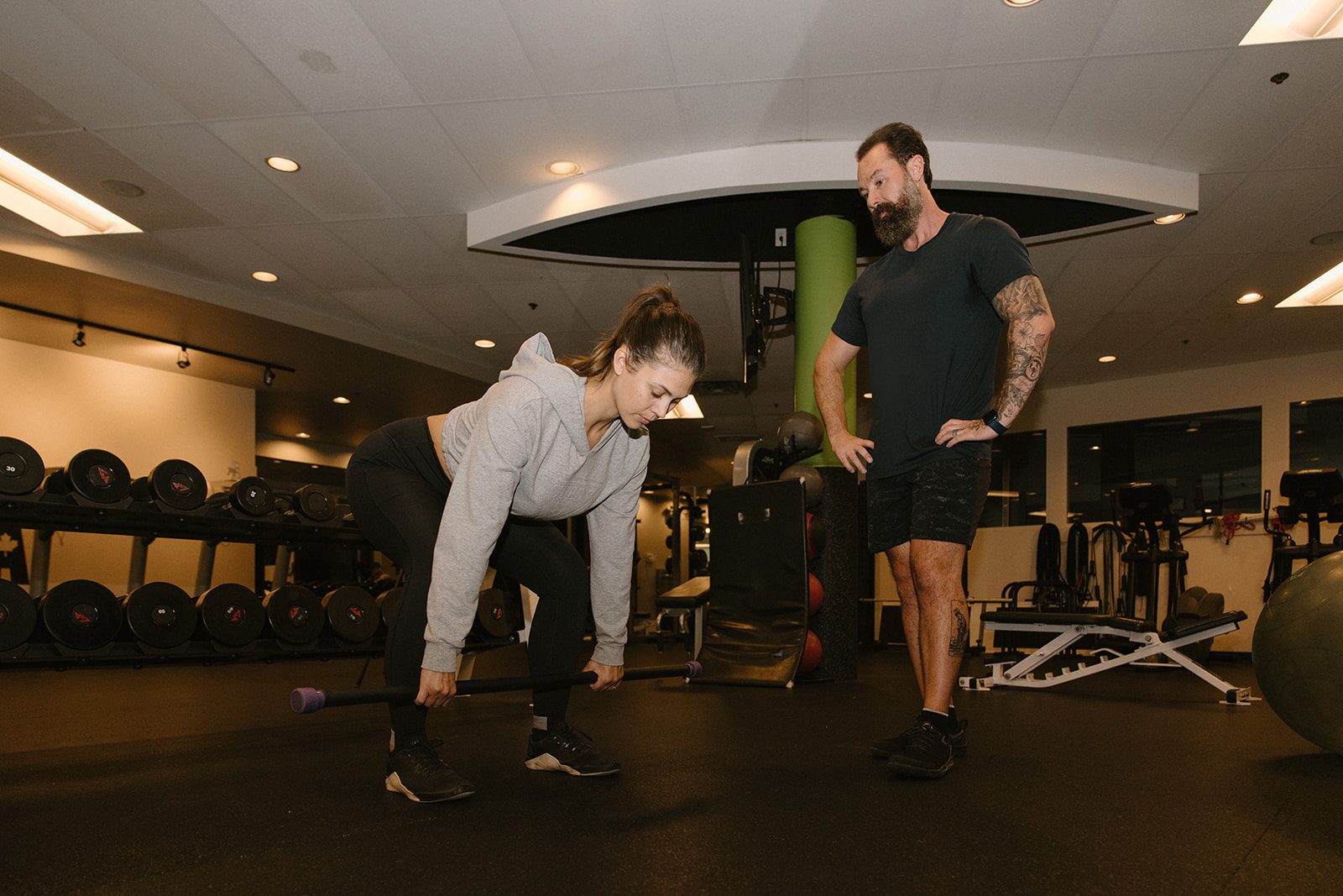 TurnFit coach David Turnbull cueing a midlife woman through a barbell hinge in the gym