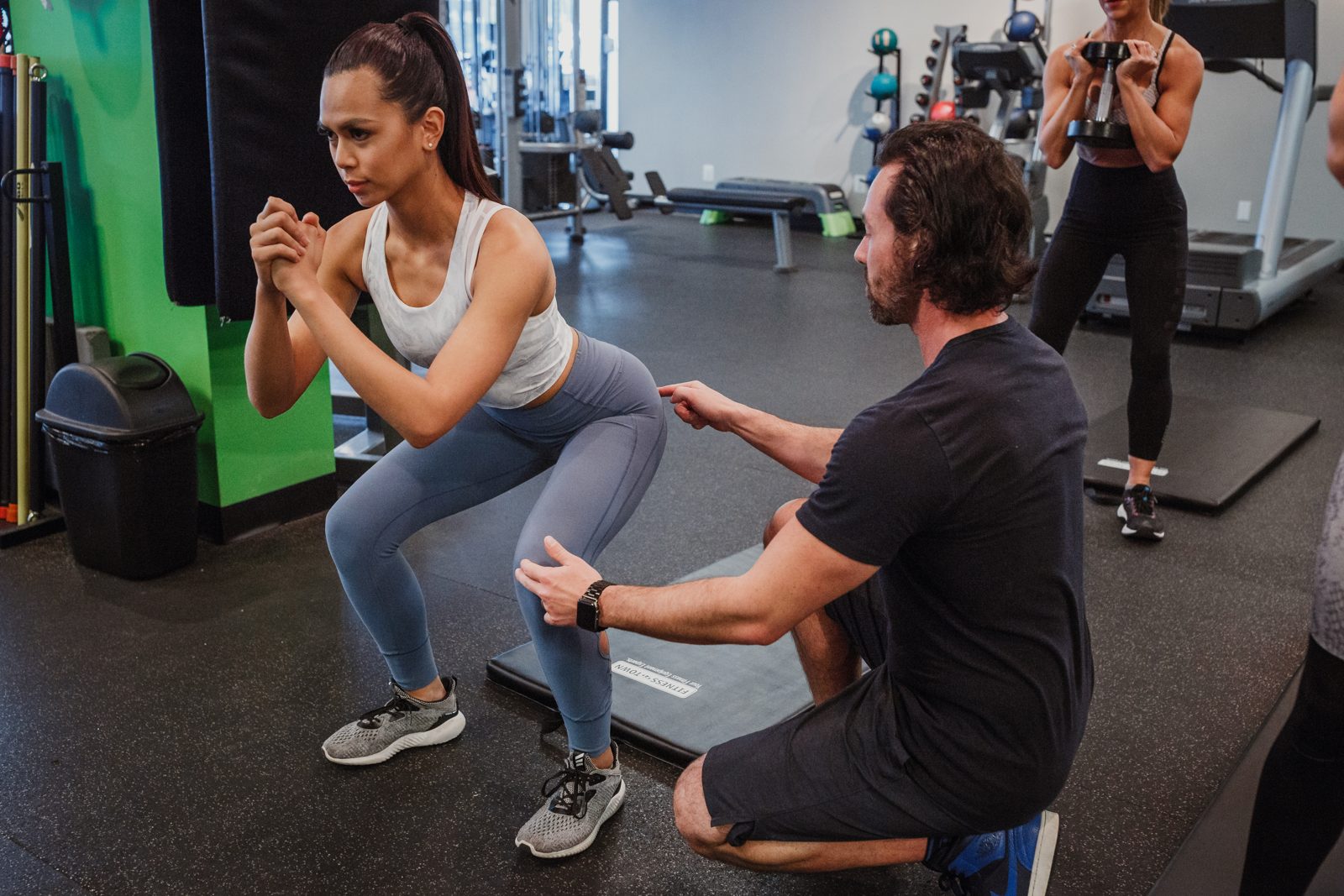 TurnFit coach cueing a squat with a midlife client — progressive form that scales from studio to remote teams