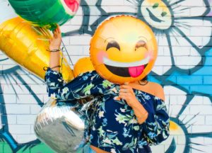 Woman having fun with a smiley faced balloon